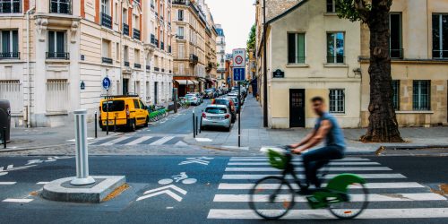 Unidentifiable,Man,Cycling,Down,The,Street,In,Paris,,France.